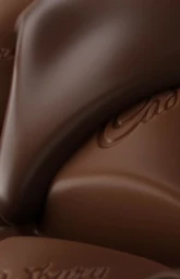 Macro shot of smooth milk chocolate blocks with glossy surfaces and embossed lettering under warm studio light