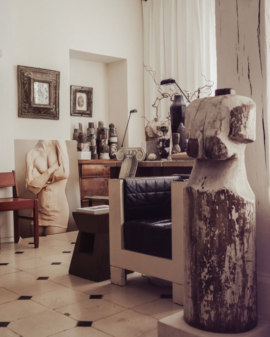 Art studio interior with classical busts, sculptures, decorative vases, art objects, and modern chair. Interior and architecture photography.