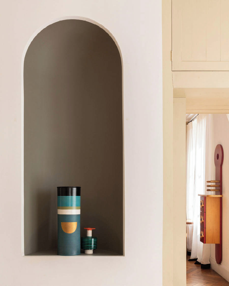 Interior shot of decorative vases displayed within a recessed arched wall niche, complemented by a cabinet with an artistic design.