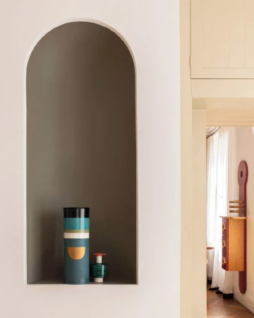 Interior shot of decorative vases displayed within a recessed arched wall niche, complemented by a cabinet with an artistic design.