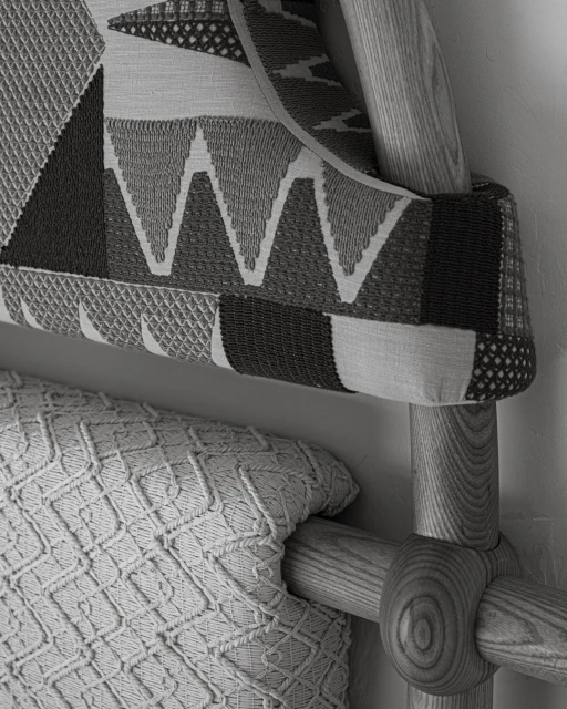 Close-up of a bed featuring a geometrically patterned headboard and a textured knit throw blanket, showcasing neutral tones and textures.