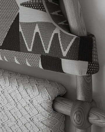 Close-up of a bed featuring a geometrically patterned headboard and a textured knit throw blanket, showcasing neutral tones and textures.
