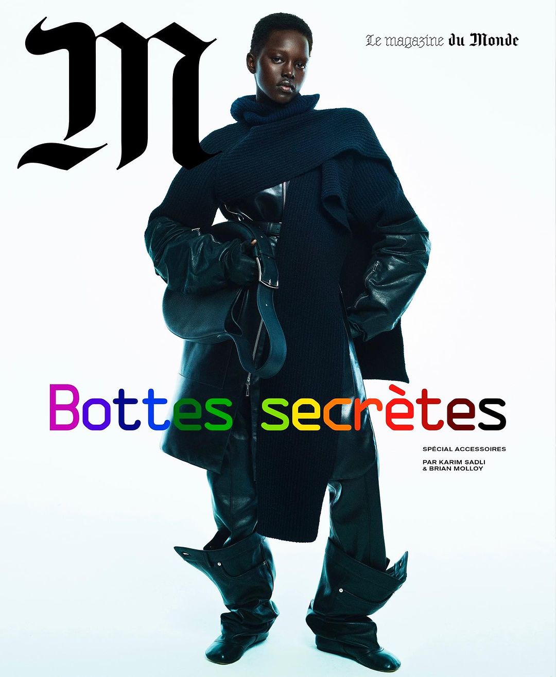 Magazine cover featuring a Black female model in a dark, oversized outfit, dramatic boots, and holding a shoulder bag against a bright backdrop.