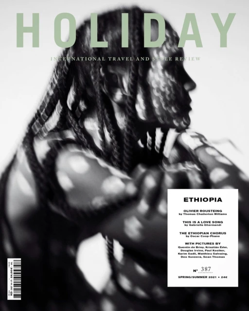 Holiday magazine cover featuring a Black model with braided hair and an abstract background. The focus is on travel and style.