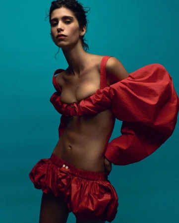 Model in voluminous red off-shoulder top and matching shorts against a solid blue background by Karim Sadli.