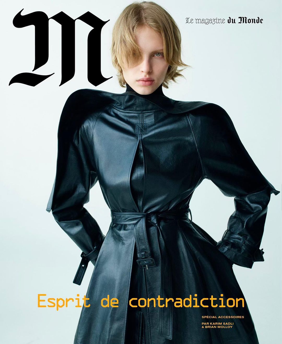 Fashion magazine cover featuring a woman in a black leather trench coat against a clean white background with bold typographic elements.