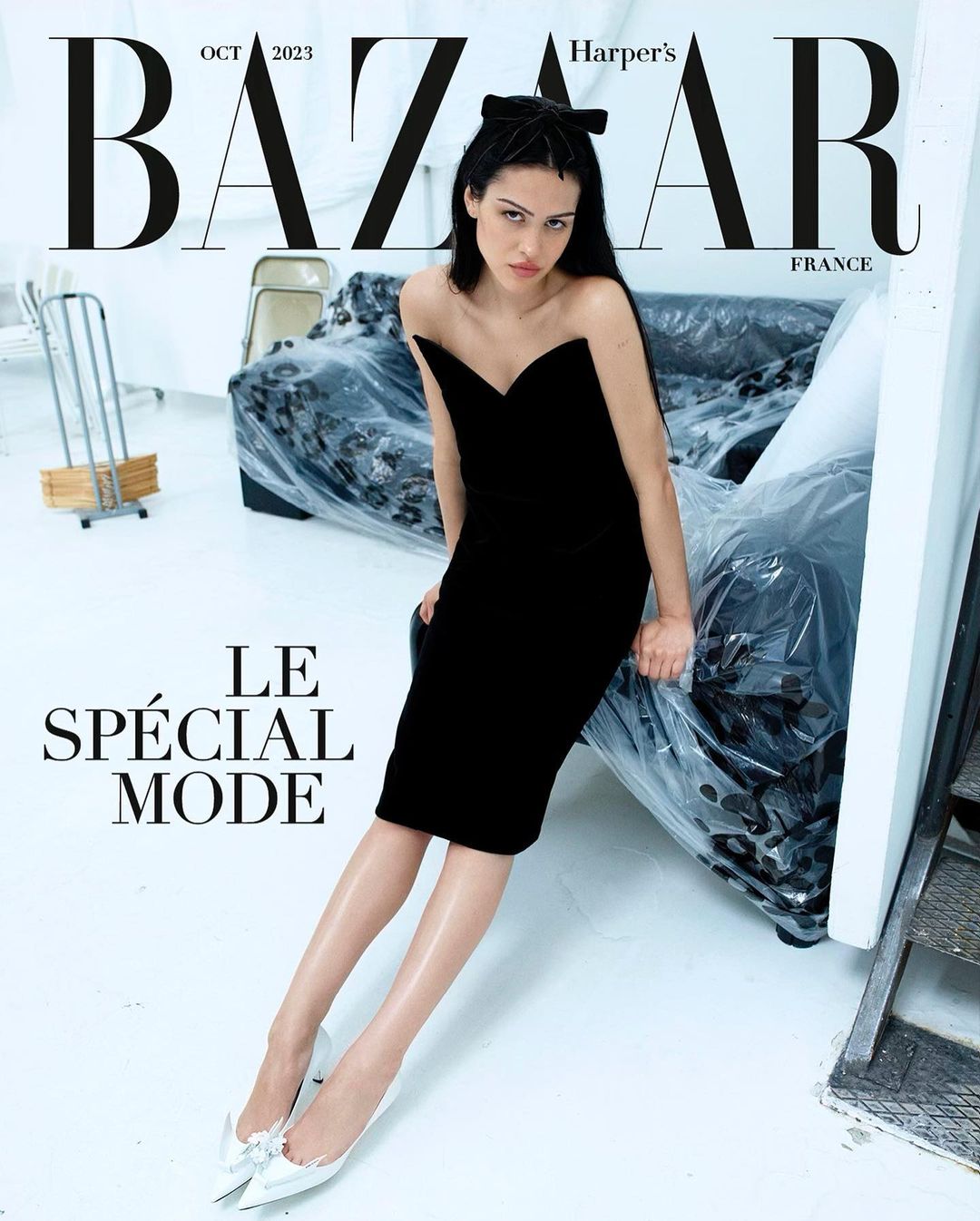 Fashion magazine cover featuring a woman in a black dress and bow, sitting in a studio with Bazaar and Harper's Bazaar text.
