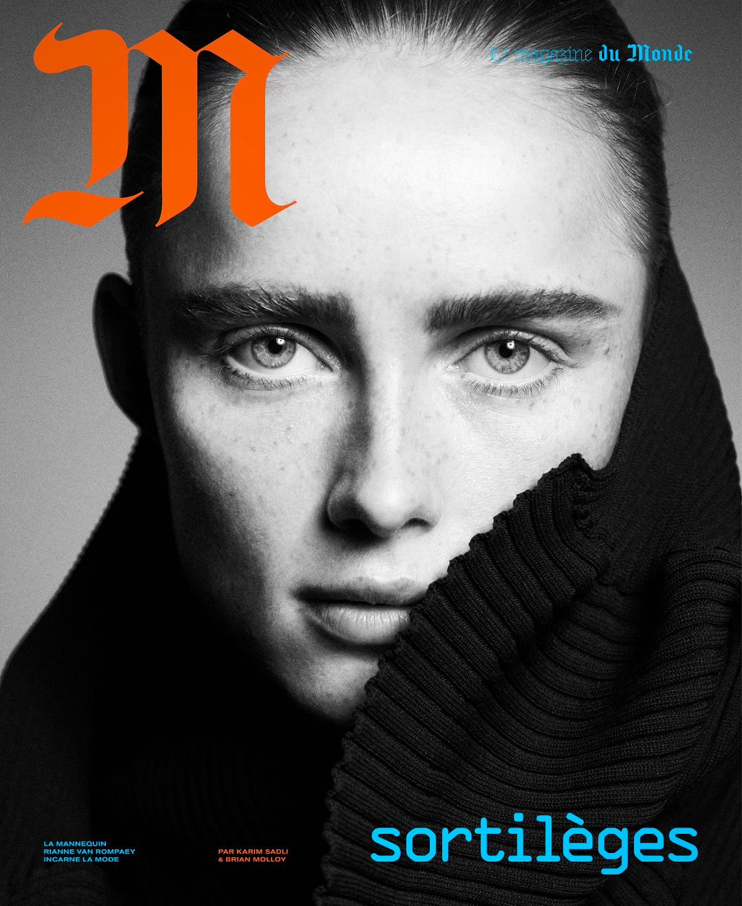Close-up magazine cover portrait of a woman with dark hair, wearing a black turtleneck, contrasted against a neutral gray backdrop.