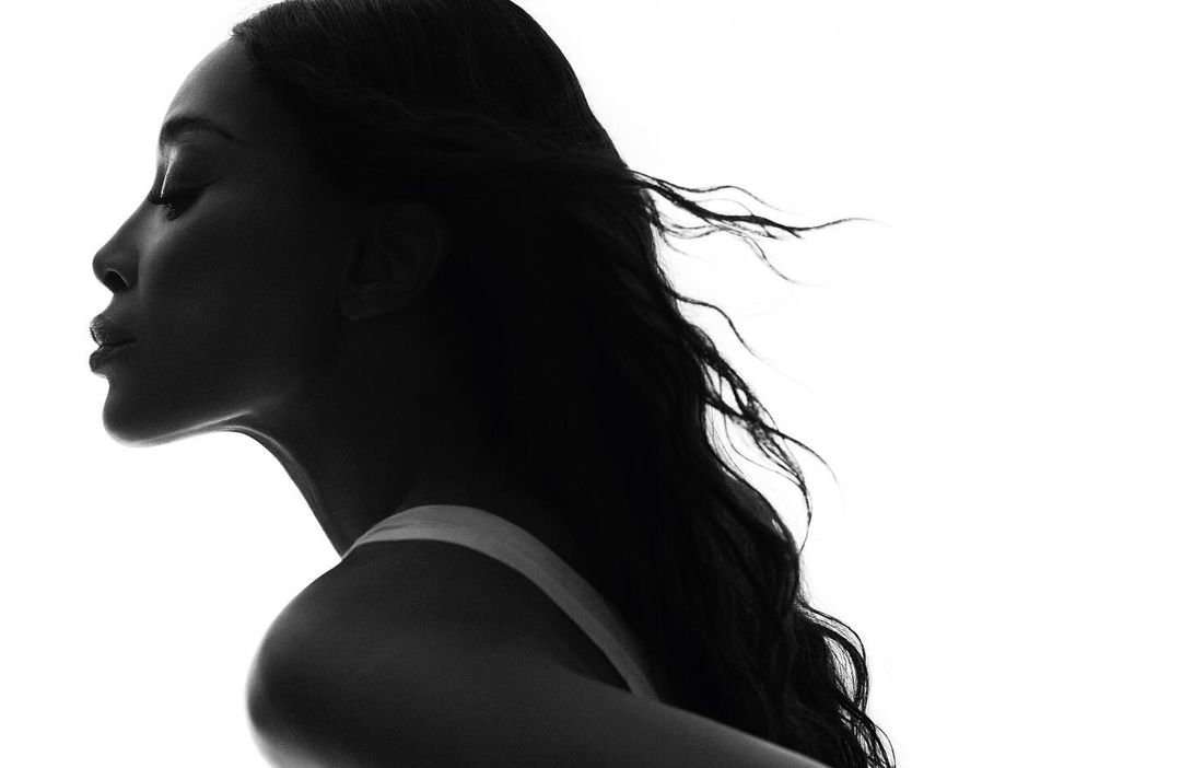 Striking black and white portrait of a woman in profile, featuring elegant, flowing hair and a minimalist fashion aesthetic.