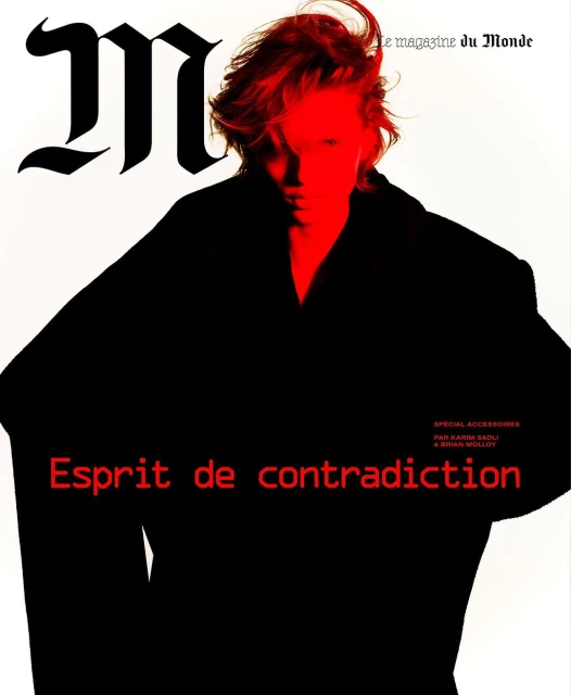 Fashion magazine cover featuring a person with red hair in a dark coat against a white background with red and black text.