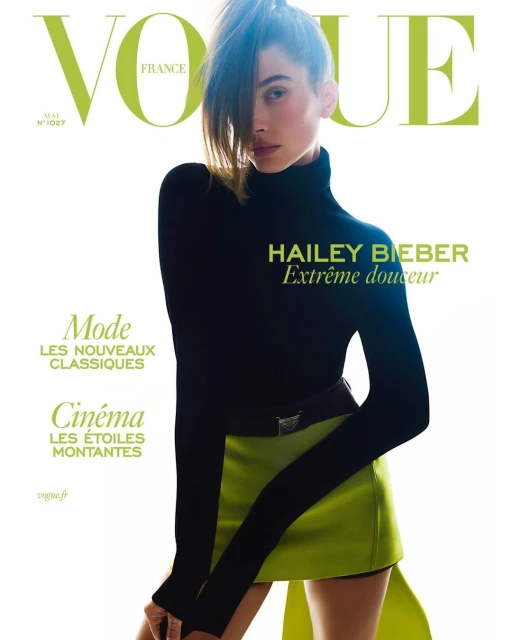 Vogue France cover featuring Hailey Bieber in a black top and green skirt, set against a bright white background. Fashion editorial.