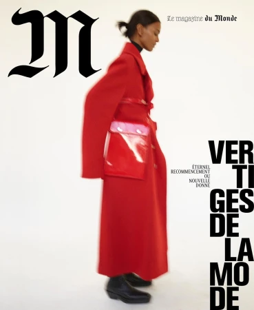 Model wearing a vibrant red coat and carrying a red handbag against a plain white background