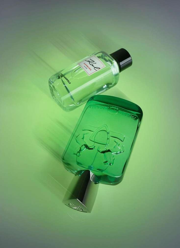 Two perfume bottles, one clear and one green, are displayed against a gradient green backdrop with soft lighting, conveying a fresh aesthetic.