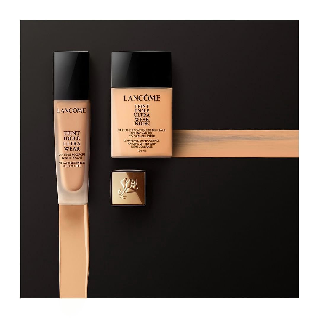 Lancôme Teint Idole Ultra Wear foundation products in square and bottle shapes with gold accents on a dark background.