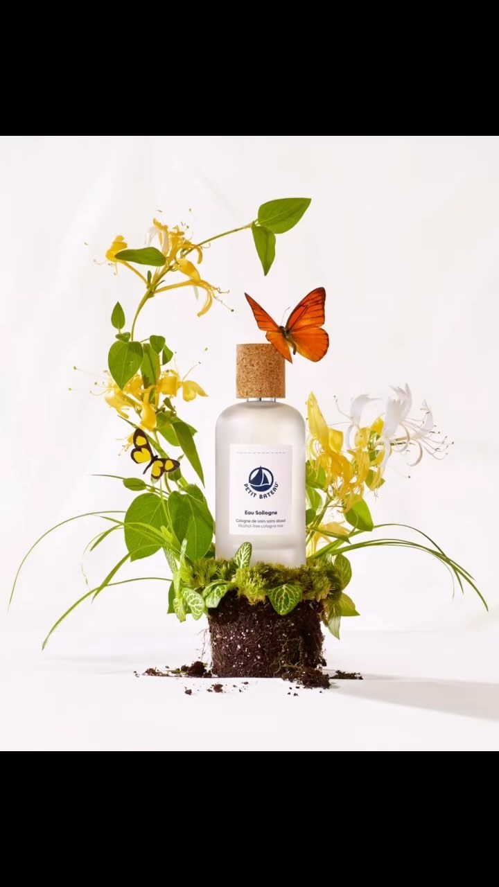 Eau de Cologne bottle amidst flowers and butterflies, studio shot on white background, product photography for beauty and personal care ad.