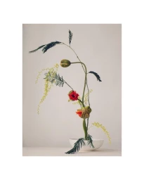 Minimalist floral arrangement in a white bowl featuring green stems, small yellow flowers, and red blooms.