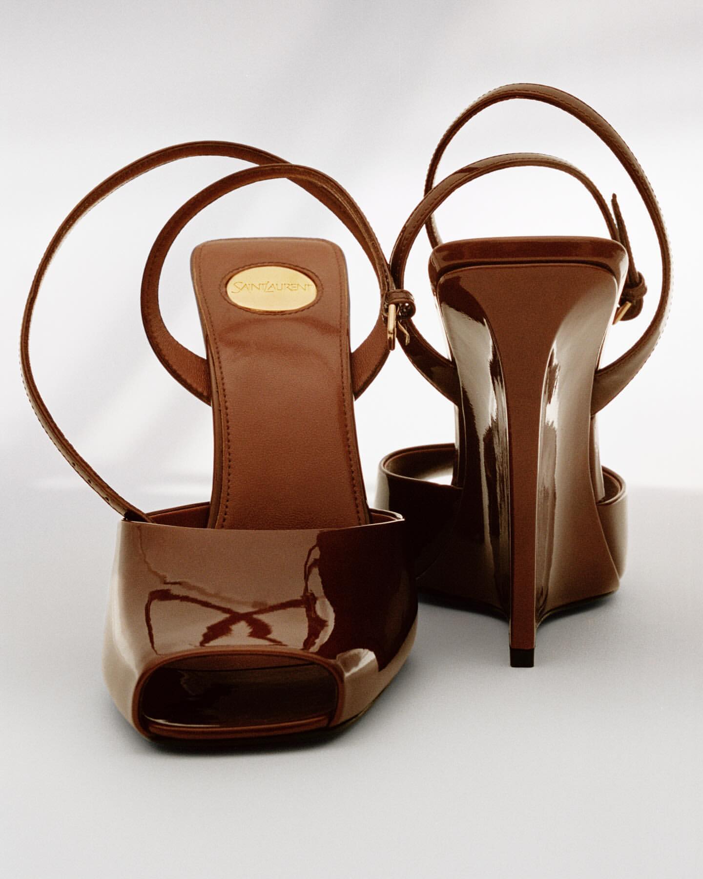 Striking studio shot of brown patent leather open-toe stiletto heels with ankle straps, showcasing a blend of elegance and modern design.
