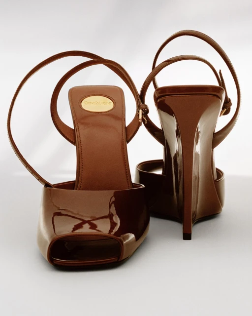 Striking studio shot of brown patent leather open-toe stiletto heels with ankle straps, showcasing a blend of elegance and modern design.