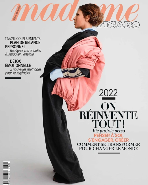 Magazine cover featuring a young woman in a black suit with a pink coat draped over her shoulder, alongside bold magazine text.