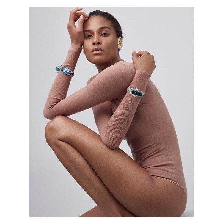 Portrait of an adult female model wearing bracelets and posing in a photo studio with neutral lighting, showcasing fashion and beauty.