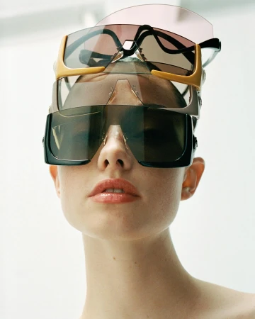 Close-up portrait of a woman wearing multiple stacked pairs of designer sunglasses on her head by photographer Karina Twiss.