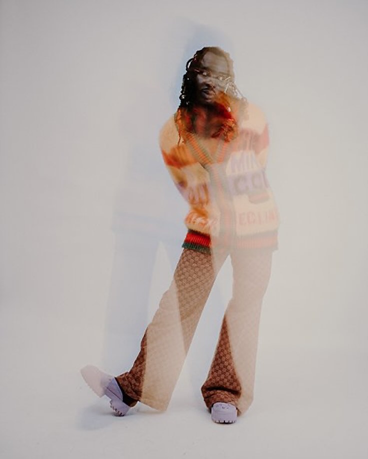 Person in multi-exposure, wearing a colorful shirt with stripes, patterned trousers and lilac clogs, posing in a photo studio.