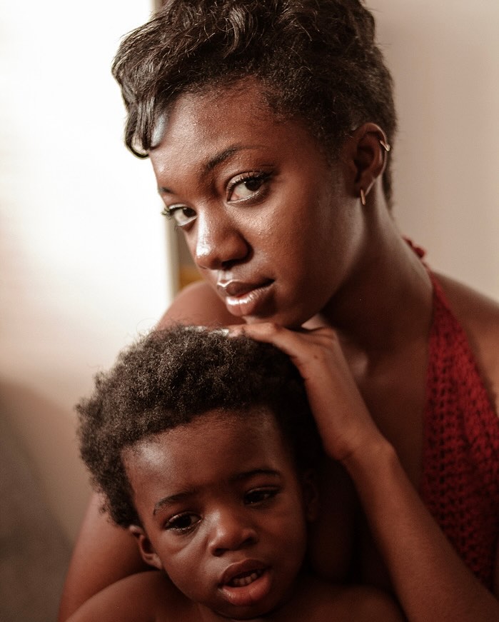 Mother and child portrait: African American woman holds her son, close-up shot with a shallow depth of field indoors.