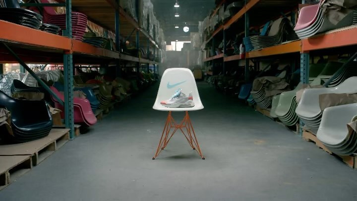 Nike shoe on a chair in a warehouse with rows of chairs. The chair has a Nike logo. Shelves with chairs extend into the background.