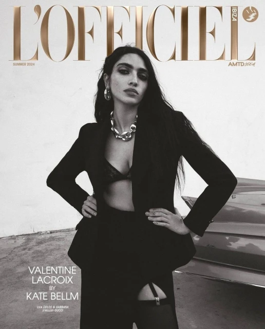 L'Officiel Ibiza Summer 2024 cover featuring a woman in a black blazer, bralette, and stockings, posing with hands on hips near a car.