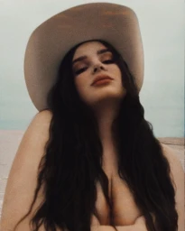 Portrait of a woman wearing a light-coloured cowboy hat against an outdoor sky background by photographer Kate Bellm.