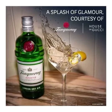 Tanqueray London Dry Gin bottle next to a martini glass with lemon twist and splash, against a grey gradient background.