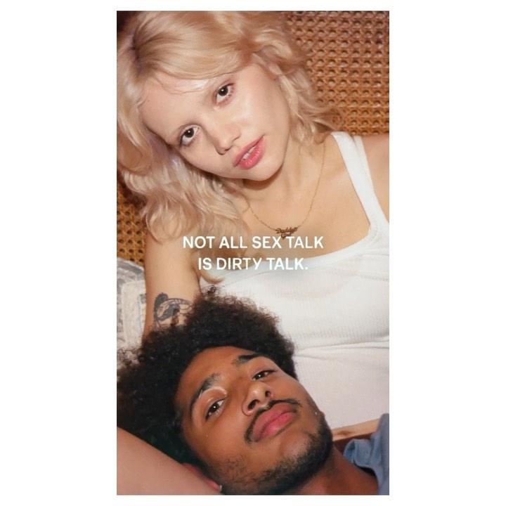 Close-up portrait of a blonde woman resting her head above a man with dark curly hair against a woven rattan background.