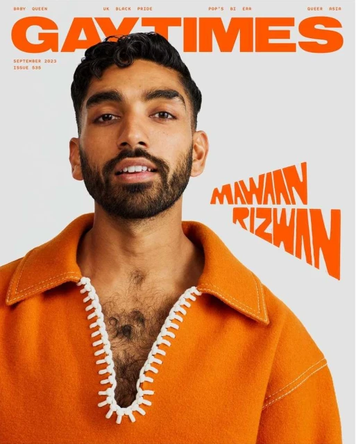 Mawaan Rizwan on the cover of Gay Times, September 2023 issue, in bright orange top with white trim, looking at the camera.