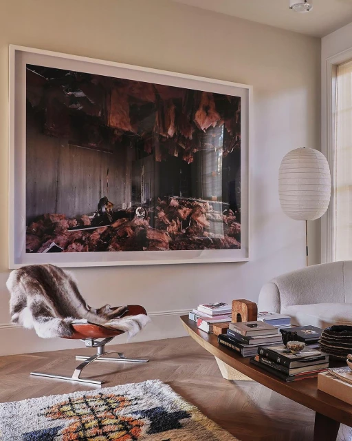 Living room features a leather chair, patterned rug, coffee table with books, and a framed photograph of an interior space.