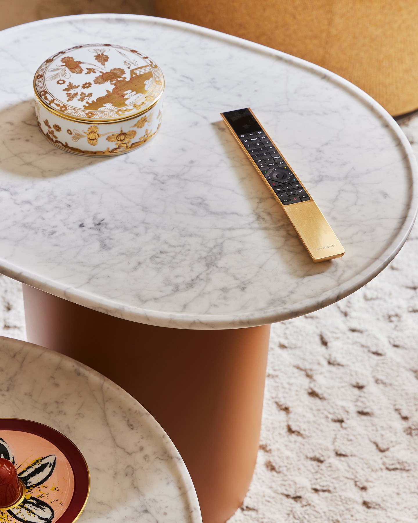 Close-up shot of a marble table featuring a decorative box, and a remote control in an indoor setting, emphasizing luxury home decor.