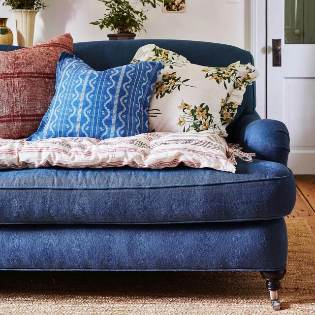 Comfortable blue couch decorated with an assortment of throw pillows in a cozy indoor setting, evoking a sense of relaxation and home decor.