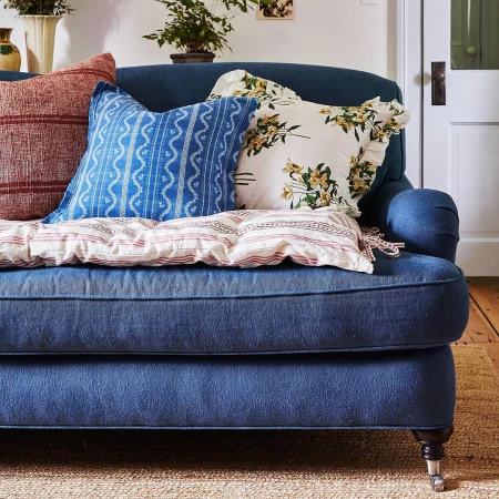 Comfortable blue couch decorated with an assortment of throw pillows in a cozy indoor setting, evoking a sense of relaxation and home decor.