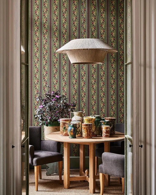 Interior dining room with a round wooden table surrounded by gray chairs, adorned with antique-style vases under a straw pendant light.