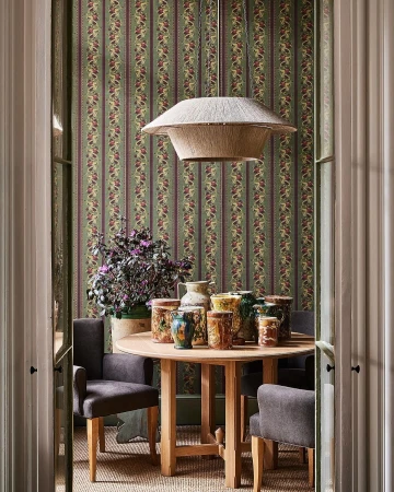 Interior dining room with a round wooden table surrounded by gray chairs, adorned with antique-style vases under a straw pendant light.