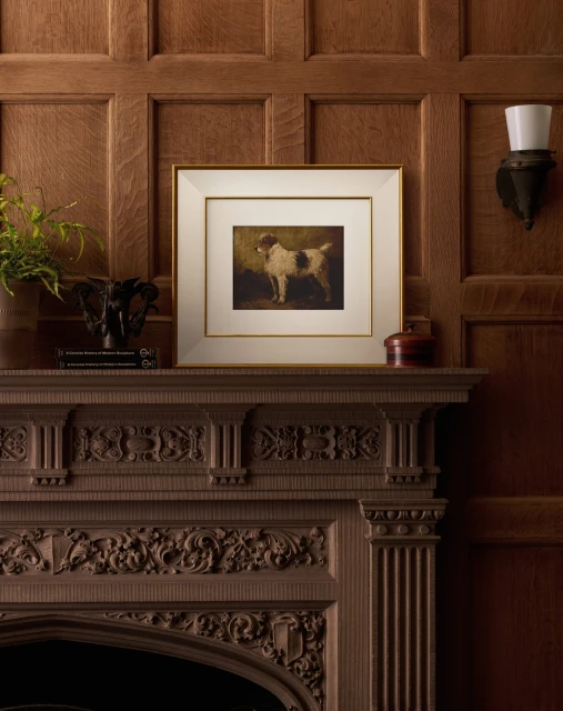 Artwork featuring a brown and white dog in a gold frame above a detailed wooden fireplace mantel in a traditionally styled room.