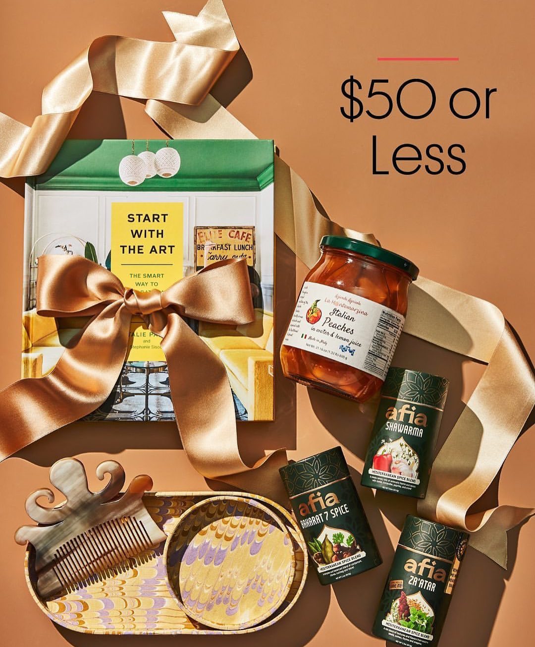 Still life shot of a gift set featuring a book, a jar of peaches, hair comb, decorative dishes, and spice containers on a brown background.