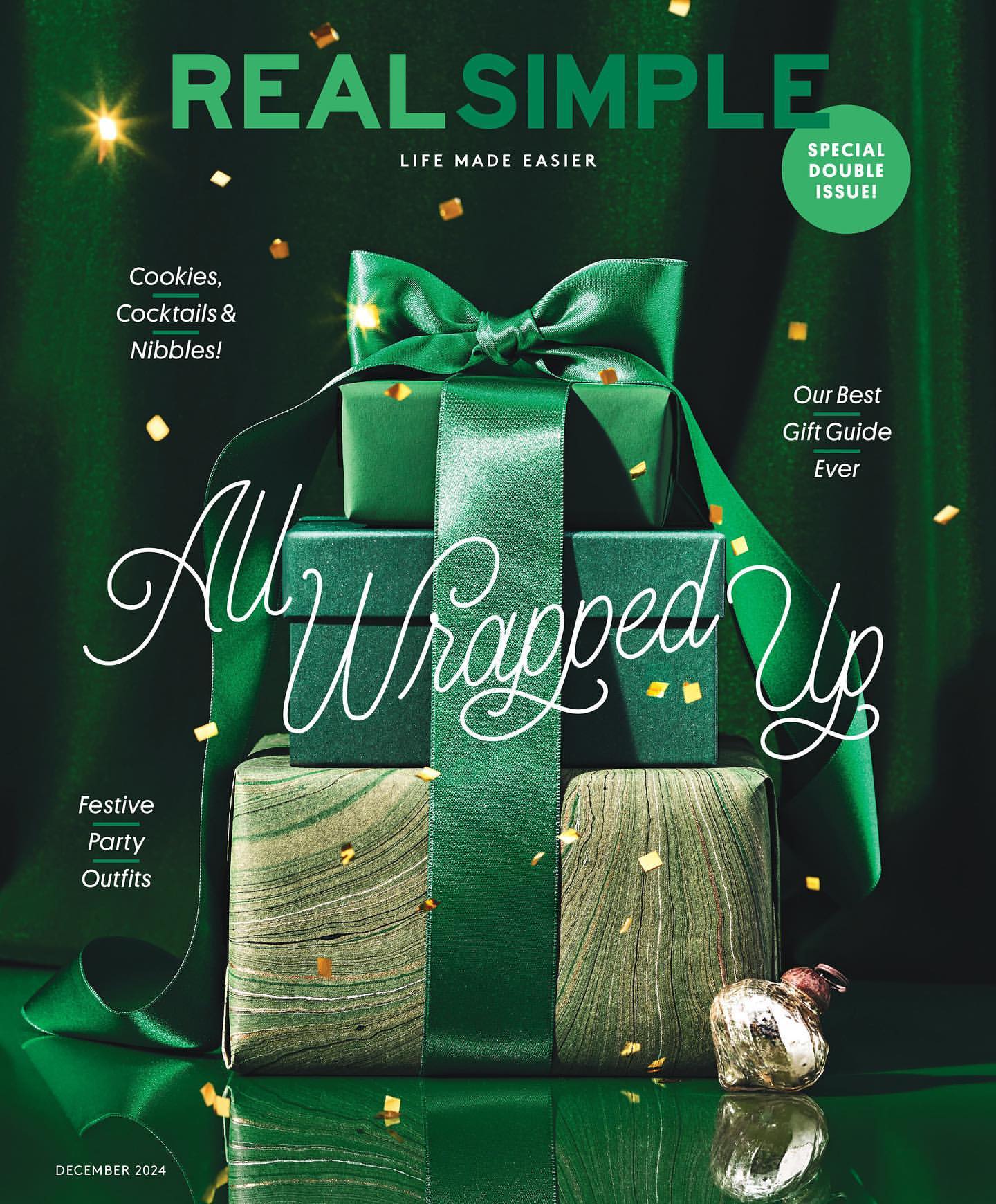 Stacked gift boxes wrapped with green ribbons on a magazine cover. Festive holiday theme with sparkling confetti against a dark green backdrop.