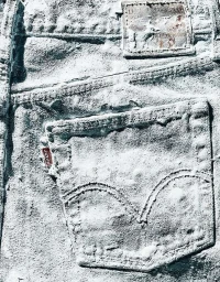 Macro shot of denim fabric covered in thick white texture with visible pocket and stitching details captured by Kate Mathis