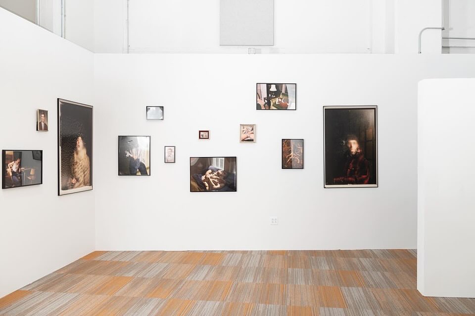 Gallery wall featuring framed art prints of various sizes and subjects, set against a white wall in a room with a patterned floor.