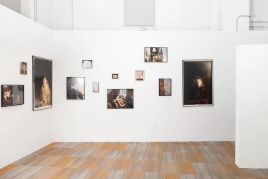 White gallery walls display framed photographic prints in an exhibition space with patterned carpet.
