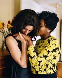 Two women holding hands and embracing indoors, photographed by Kate Warren in New York.
