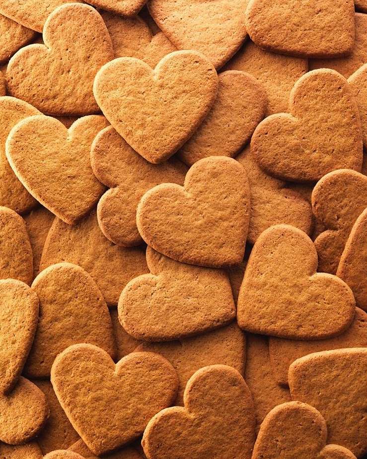 Overhead shot of a pile of heart-shaped cookies, golden brown and baked until slightly crisp, creating a textured background.