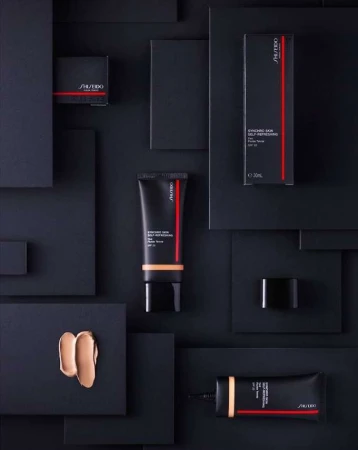 Shiseido Synchro Skin Self-Refreshing foundation products, including tube, compact and box, displayed on a geometric black background.