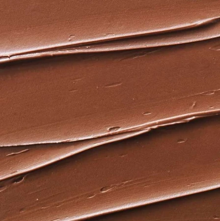 Close-up texture of a thick, brown spread with a rippled pattern; the food industry and creamy textures for culinary designs.