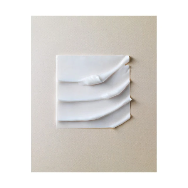 Close-up studio shot of white cream texture on a neutral beige surface. Beauty product concept with minimalist composition.